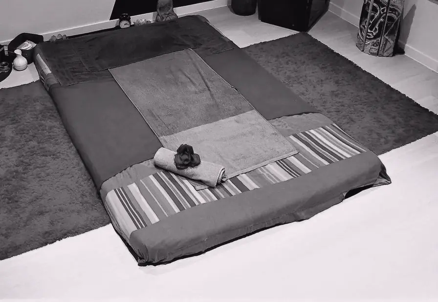 Un futon posé au sol, entouré de tapis.